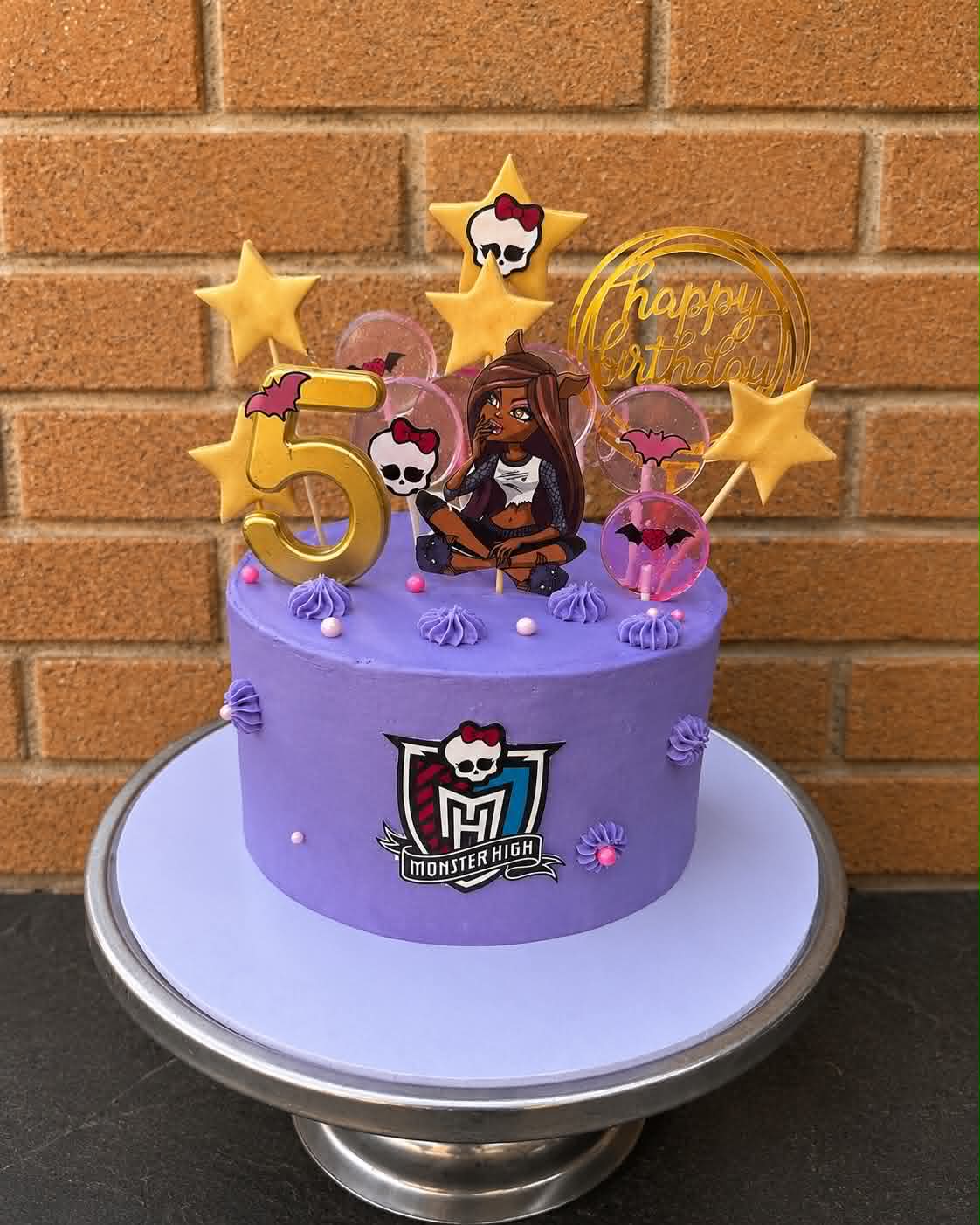 Purple Monster High 5th birthday cake with Clawdeen Wolf edible print, Monster High logo, gold star cookies, bubble lollipops, gold number 5 candle and Happy Birthday hoop topper